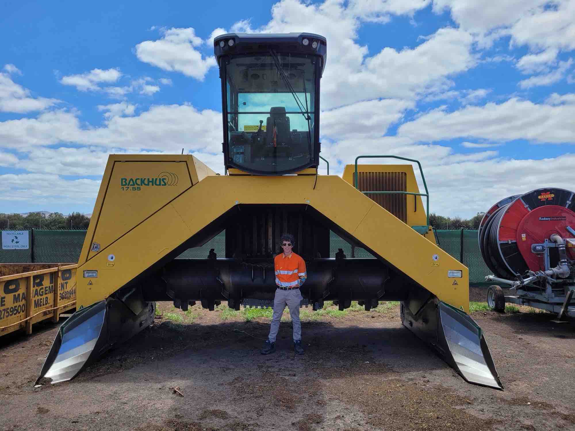 Patrick Blampied standing under a Backhus compost turner at a commercial composting facility